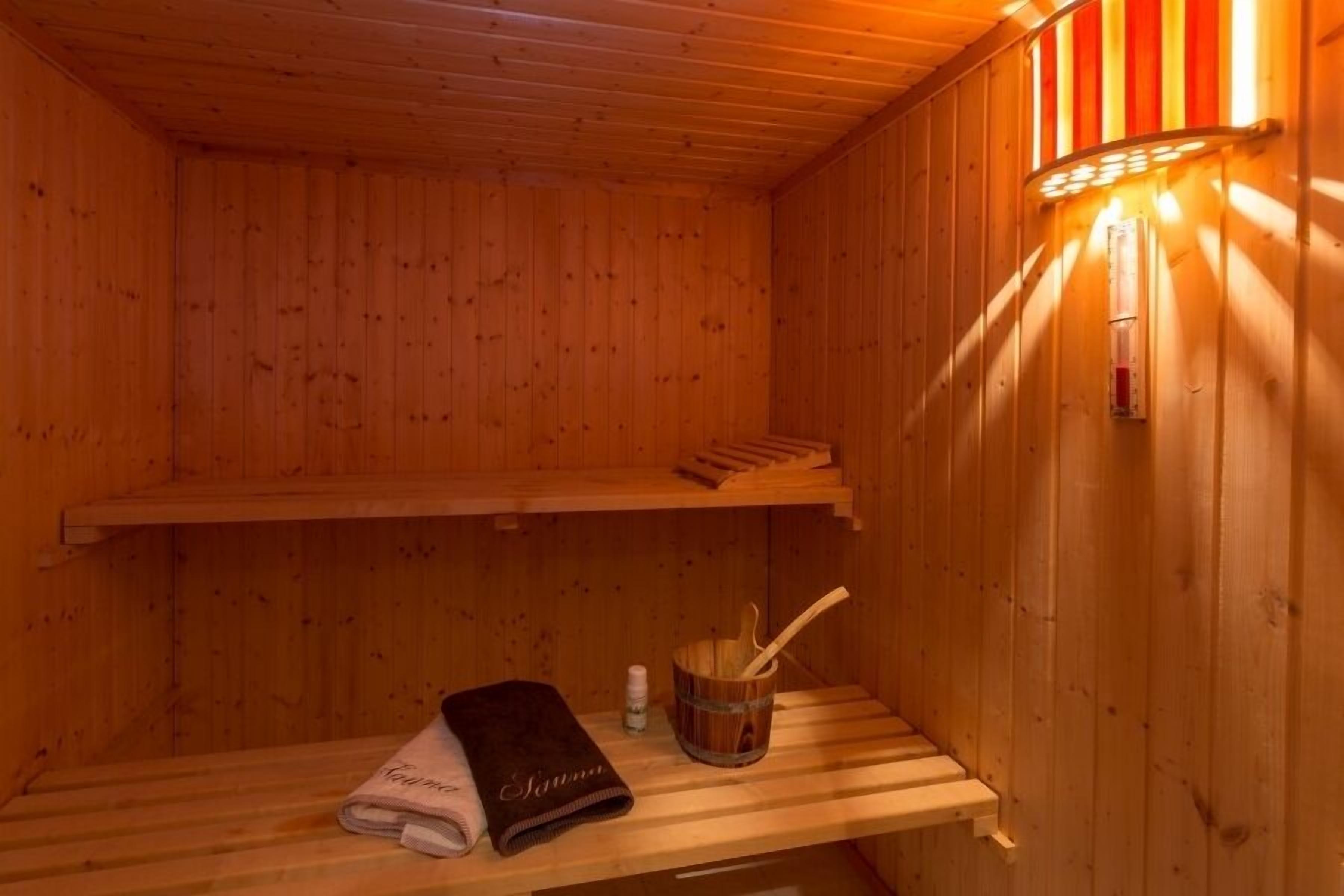 Un sauna de madera con un banco, una toalla y un balde con un cepillo.