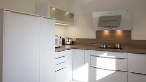 A modern kitchen with white cabinetry, a microwave, a toaster, and a built-in oven.
