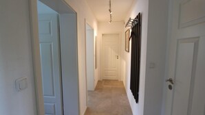 A narrow hallway with white doors, a light fixture, and a wall-mounted rack.