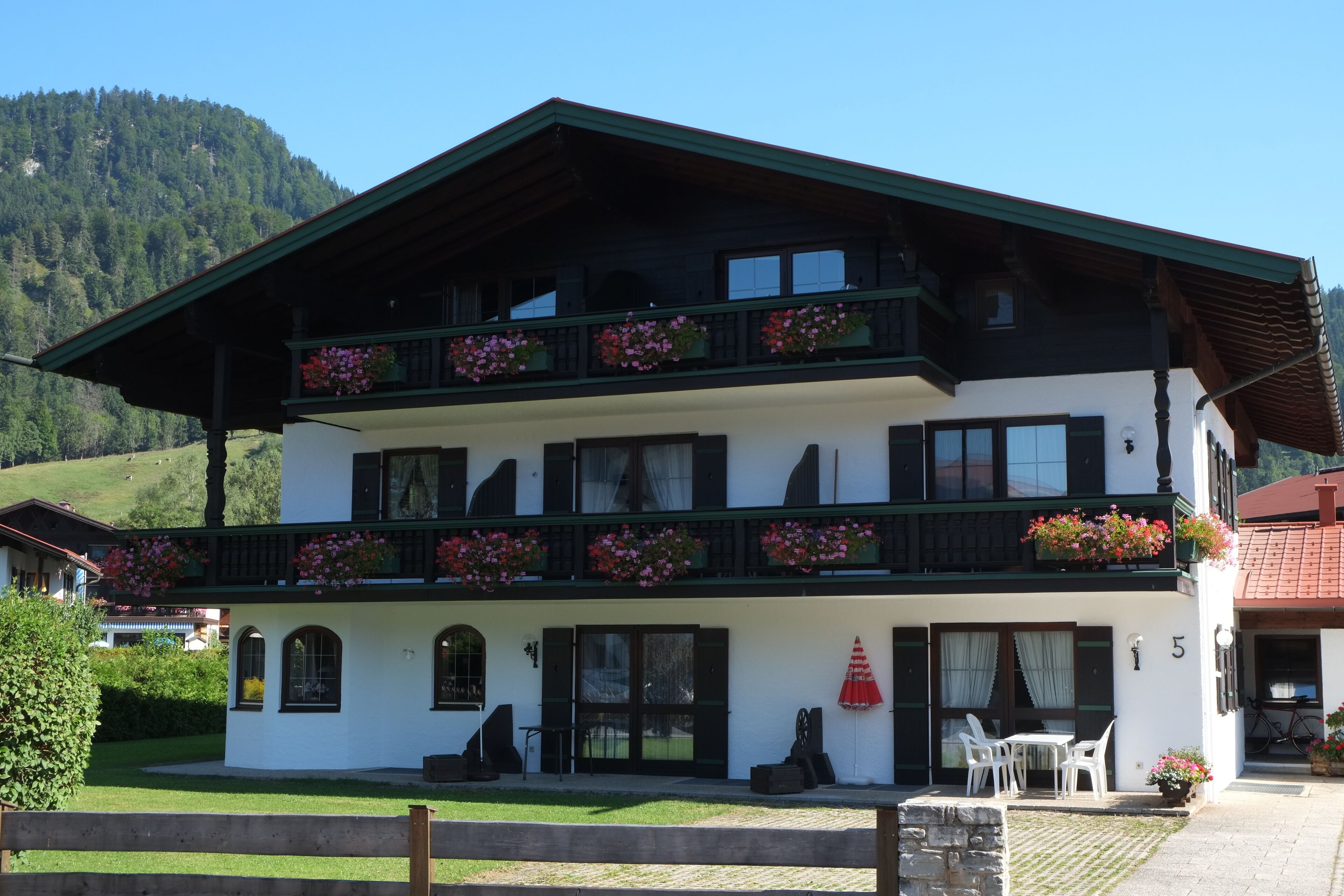 A two-story building with balconies, outdoor seating, and a mountain backdrop.