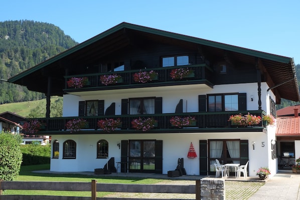 A two-story building with balconies, outdoor seating, and a mountain backdrop.