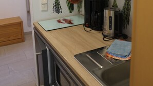Ett modernt kök med grå skåp, en diskho i rostfritt stål och en bänkskiva med en kaffebryggare och en vattenkokare.