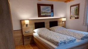 A double bed with a wooden headboard, two bedside tables with lamps, and two framed paintings on the wall. - Ferienwohnung 3 (Berchtesgaden)