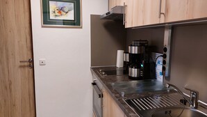 A compact kitchen with a coffee maker, a sink, and a framed artwork on the wall. - Ferienwohnung 3 (Berchtesgaden)
