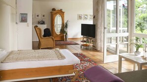 Une chambre à coucher avec un lit, une chaise, une télévision, un miroir et une fenêtre.