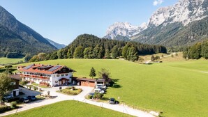 A hotel with a red-tiled roof, a parking area, and a view of mountains and forested hills. - Apartment no. 6, 1-4 persons, 60 sqm, balcony, W-LAN, 1 bedroom and 1 children's bedroom (Ramsau bei Berchtesgaden)