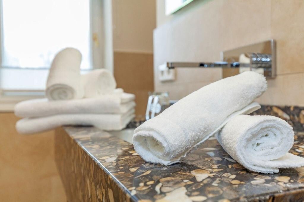 A bathroom with a marble countertop, a towel rack, and a towel folded on the counter.