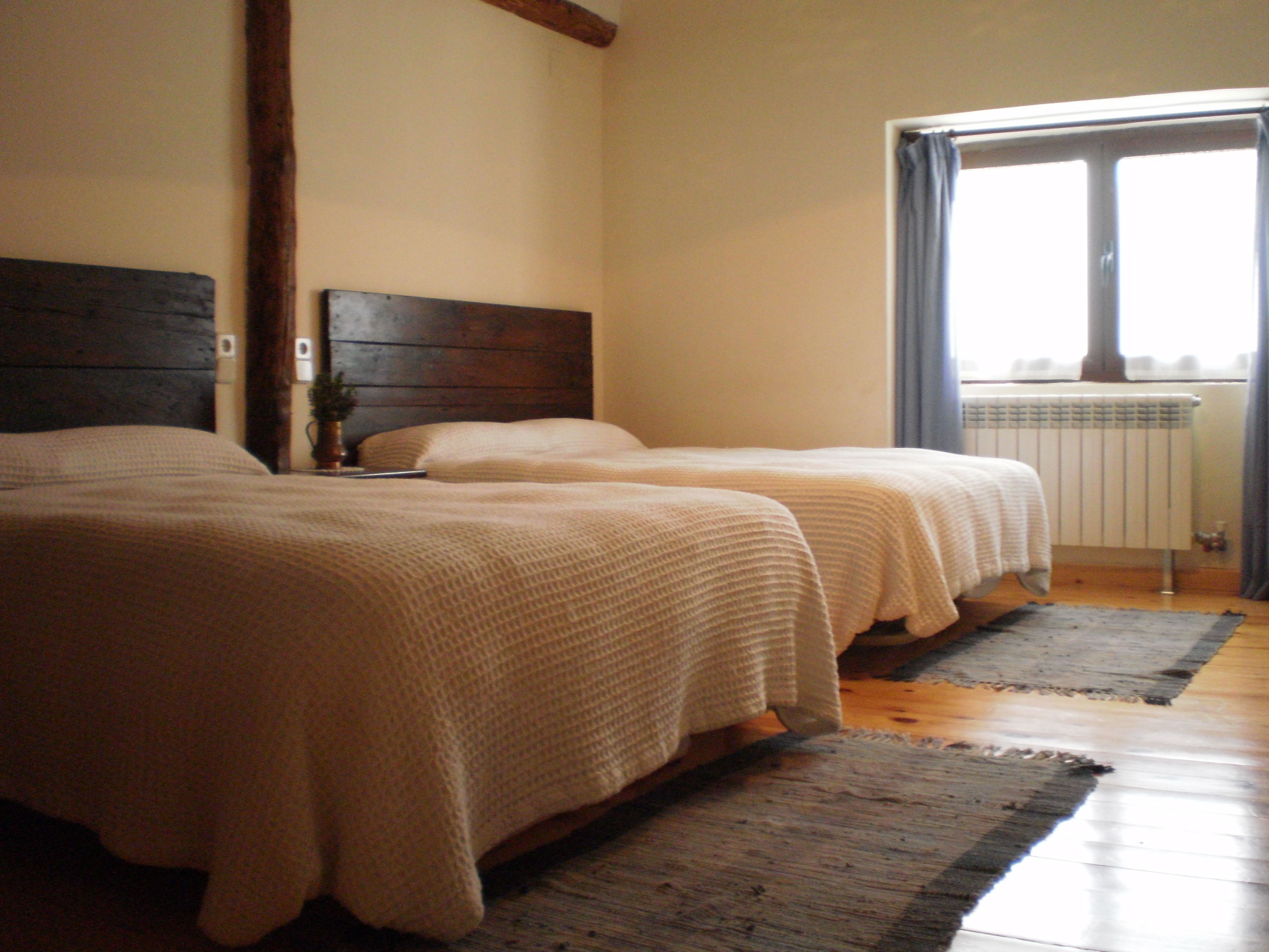 Habitació amb dos llits, ambres de fusta i una finestra que dona a una vista.