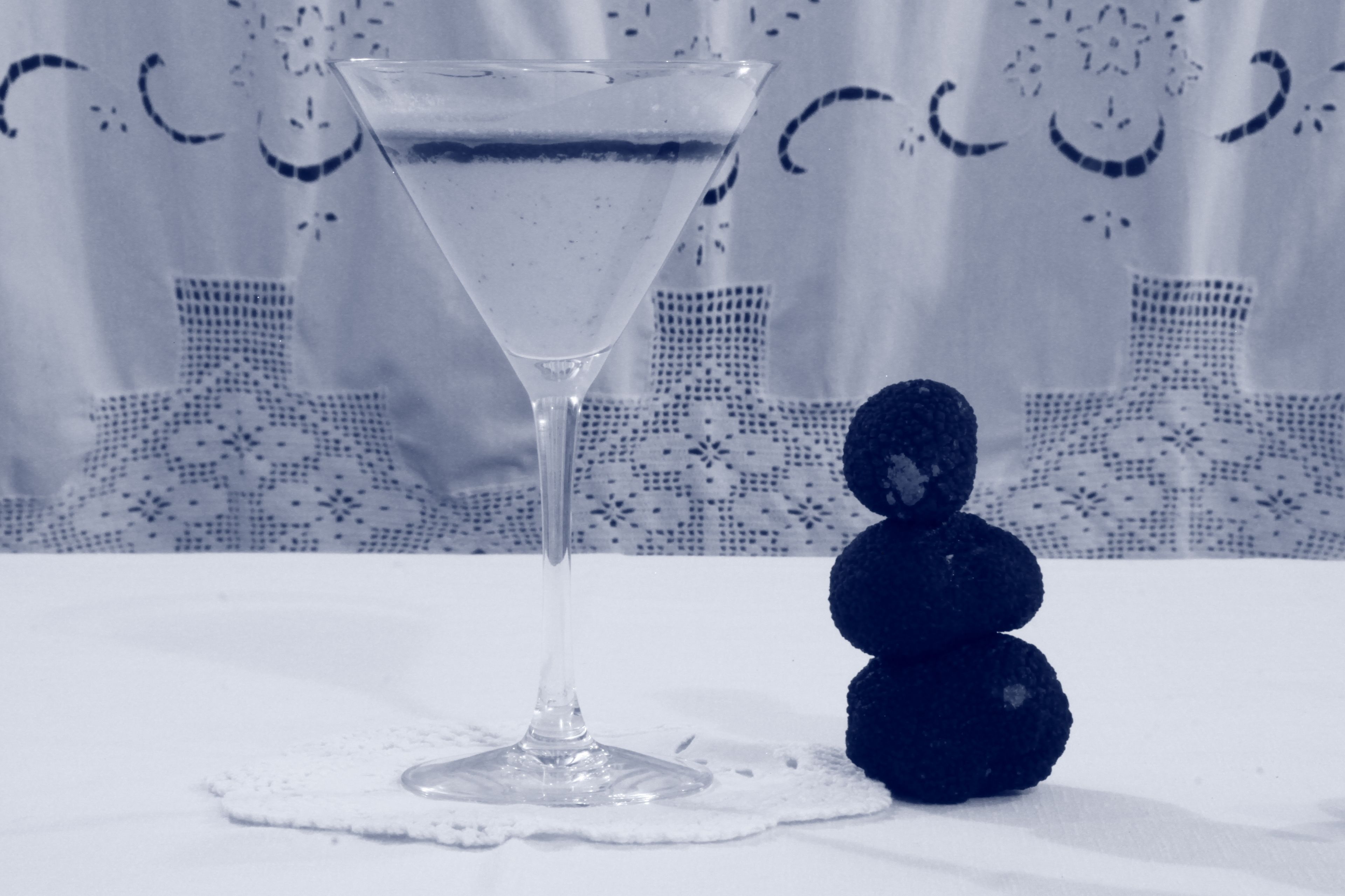 Una copa de martini con un líquido transparente sobre un mantel blanco.