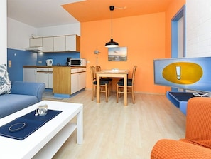 A compact living space with a kitchenette, a dining area, and a seating area with a television.