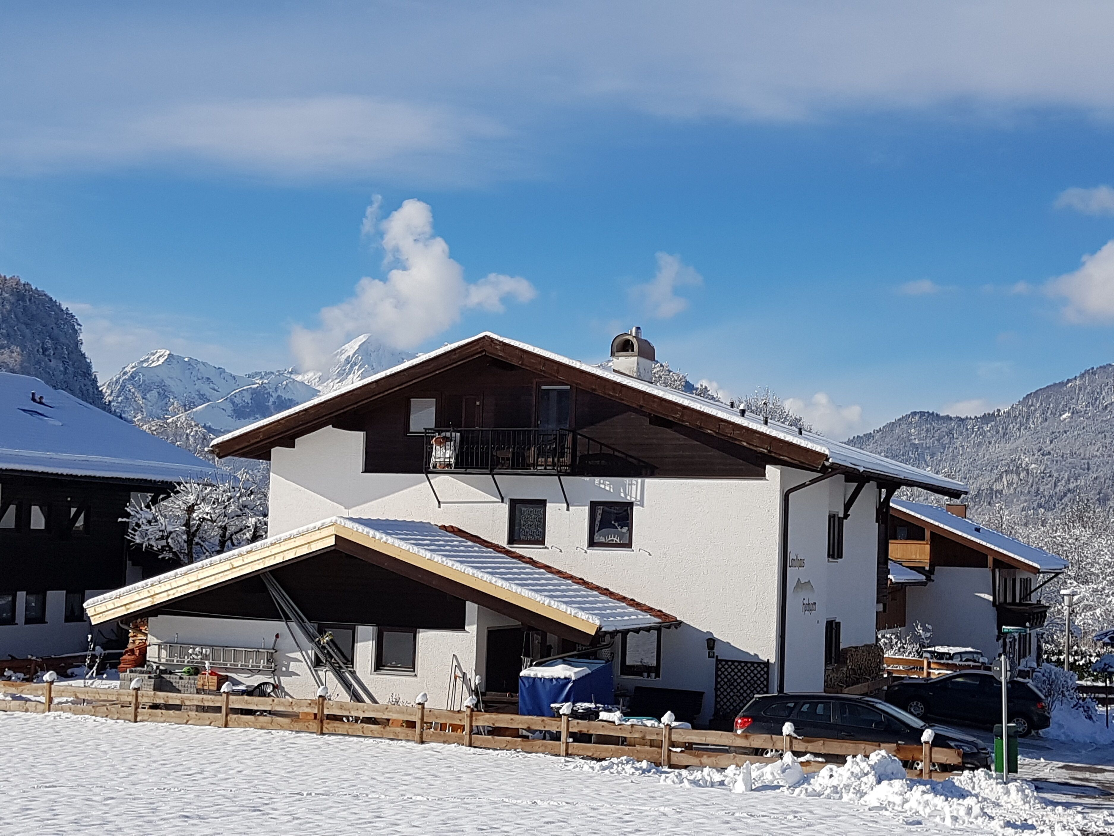 A two-story chalet with a sloped roof, a balcony, and a ski lift in the foreground.