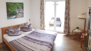 Une chambre à coucher avec un lit, un tableau, une chaise, une table et une vue sur l’extérieur.