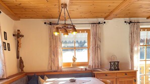 A cozy dining area with a wooden table and chairs, a bench, and a cross on the wall. - Nr. 1, Ferienwohnung 2-4 Pers. mit 2 Schlafzimmern, Wohnküche, Dusche/WC und Balkon (Bischofswiesen)