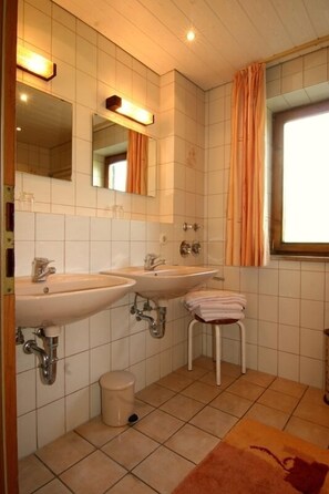 Une salle de bain avec deux lavabos, des toilettes et une fenêtre avec des rideaux.