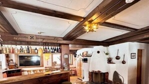 Een bar met houten stoelen, een televisie en een wijnrek.