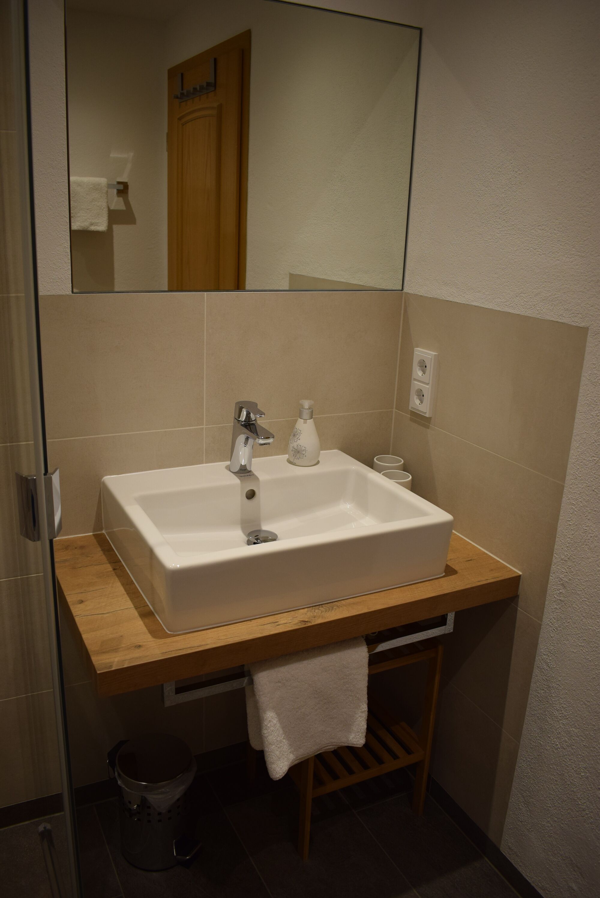 Une salle de bain avec un lavabo blanc, un plan de toilette en bois et un miroir au-dessus du lavabo.