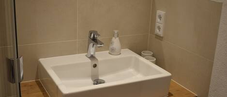 Une salle de bain avec un lavabo blanc, un plan de toilette en bois et un miroir au-dessus du lavabo.