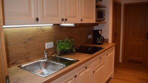 A kitchen with wooden cabinets, a stainless steel sink, a microwave, and a coffee maker. - Apartment Kienberg 38 sqm, balcony, kitchen, 1 bedroom, 1 bed-sitting room (Ruhpolding)