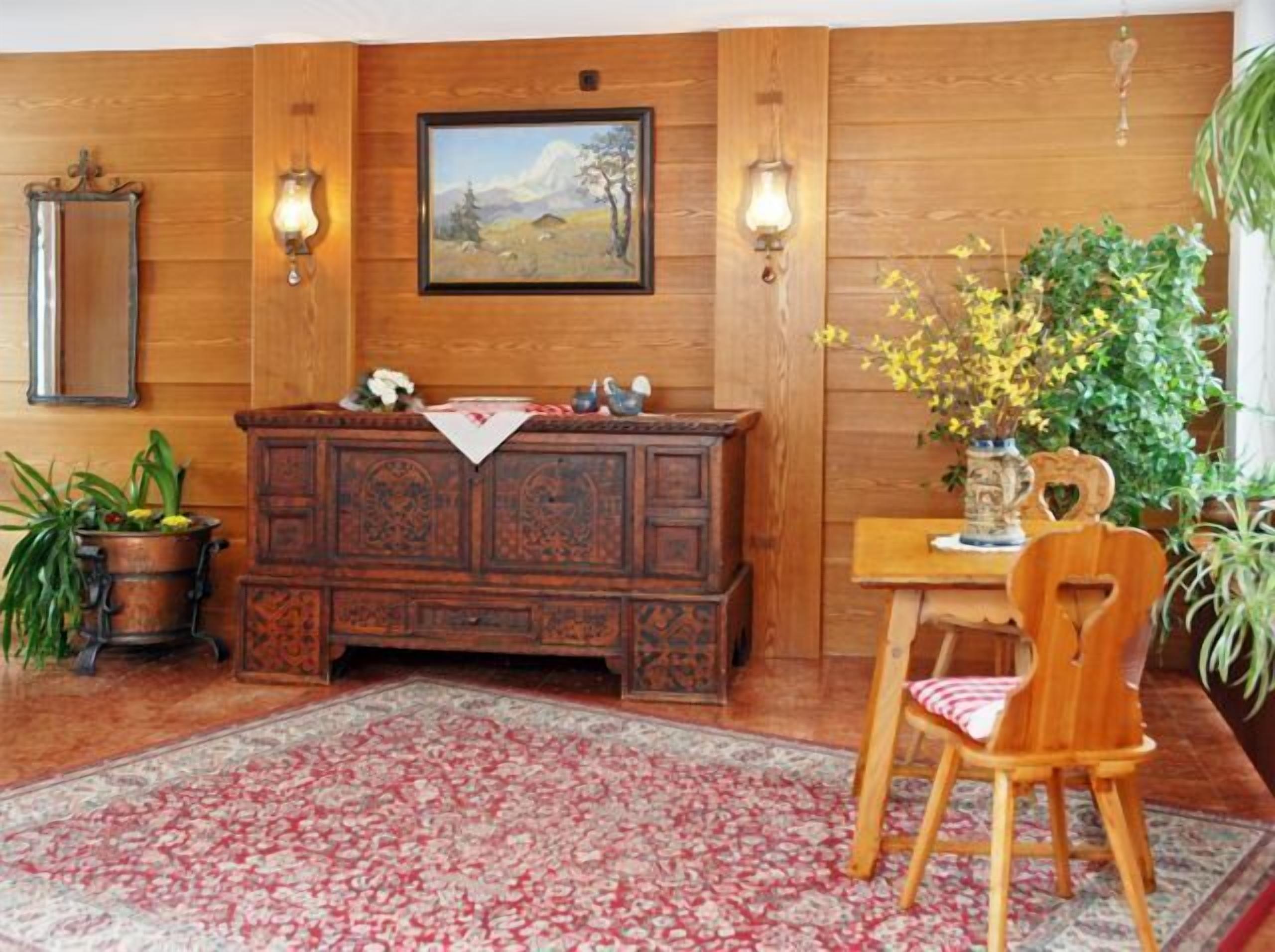 A traditional room with a wooden cabinet, a painting on the wall, and a dining area with a table and chair.