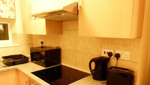 Una cucina con microonde, tostapane, bollitore e lavandino.