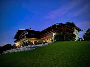 A multi-story building with a sloped roof, large windows, and a stone retaining wall. - Vacation apartment Gipfelzauber, for 1-4 persons (Berchtesgaden)