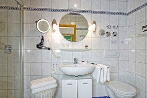A bathroom with a white sink, two mirrors, a toilet, and a shower area.