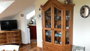 Ein Zimmer mit einem Holzkabinett, einem Fernseher und einem Esstisch.