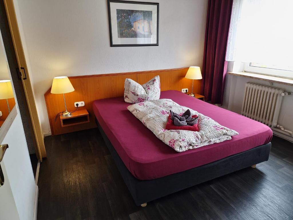 Une chambre d’hôtel avec un lit simple, deux lampes de chevet, un tableau encadré au mur et une fenêtre avec des rideaux.