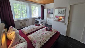 Habitación de hotel con dos camas, televisión, escritorio y ventana con cortinas.