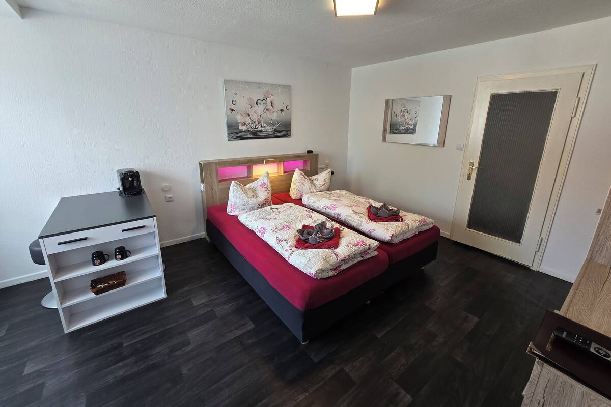 A modern bedroom with a bed, bedside tables, a desk, and artwork on the walls.