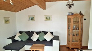 A cozy living room with a sectional sofa, a wooden cabinet, and a small table. - Ferienwohnung° II 45 qm, extra Schlafzimmer und Ost-Balkon° (Aschau im Chiemgau)