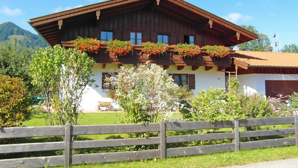 A traditional chalet with a sloped roof, wooden balcony with flower boxes, and a white facade. - Ferienwohnung° II 45 qm, extra Schlafzimmer und Ost-Balkon° (Aschau im Chiemgau)