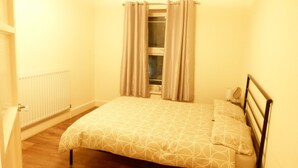 Ein Schlafzimmer mit einem Bett, einem Heizkörper und einem Fenster mit Vorhängen.
