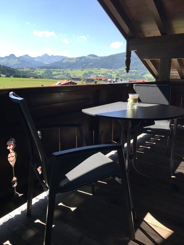 A wooden deck with a table and chairs overlooking a mountainous landscape.