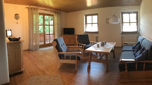 A cozy room with wooden flooring, a sofa, two chairs, a table, a TV, and a lamp. - Haus am Dürrach (Reit im Winkl)