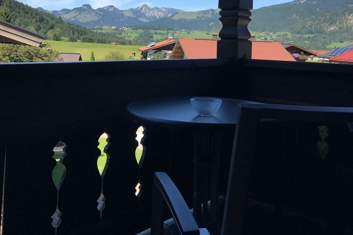 A balcony with a view of mountains and a village.