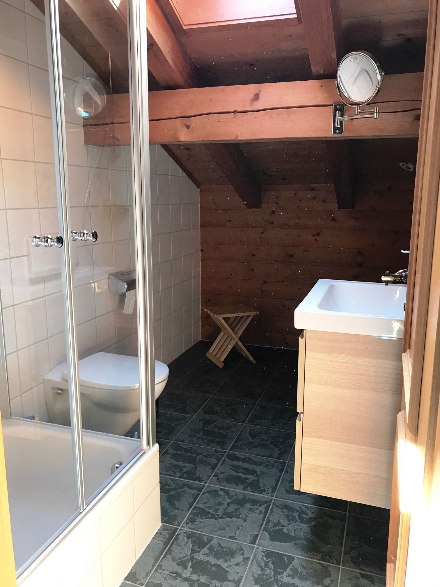 Ein kleines, rustikales Badezimmer mit Dusche, Toilette und Waschbecken.