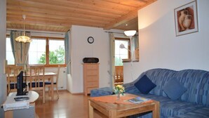 Un accogliente soggiorno con un divano blu, un tavolino in legno e una zona pranzo con tavolo e sedie.