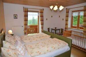 Une chambre avec deux lits, une petite table et un berceau.