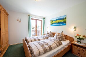 Une chambre à coucher avec un lit en bois, une table de chevet, une commode, une fenêtre avec des rideaux et un tableau accroché au mur.