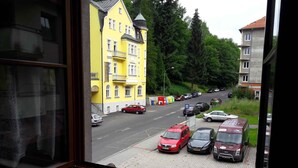 On voit un bâtiment jaune avec une enseigne indiquant « HÔTEL » et une voiture rouge garée devant.