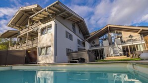 Una casa moderna de dos pisos con una piscina al frente.