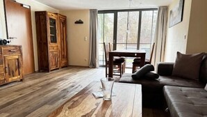 Una sala de estar con una mesa de centro de madera, un sofá, una mesa de comedor con sillas y un mueble de madera.