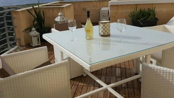 Una mesa para dos en un balcón con vista al océano.