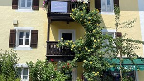 Ein gelbes Gebäude mit Balkon, geschmückt mit Blumen, und einem Schild mit der Aufschrift 'Feriendorfwohnung Marianne'.