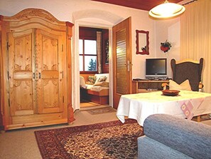 Cozy room with a traditional wardrobe, comfortable sofa, and a neatly made bed with a television and mirror.