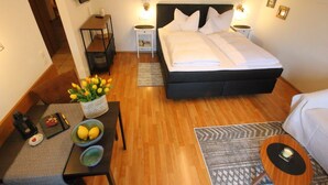 A neatly arranged bedroom with a bed, bedside tables, a small table with a vase of flowers, and a chair. - (05) Ein-Raum-Ferienwohnung 32qm, Dusche/WC, Kochnische, Balkon (Reit im Winkl)