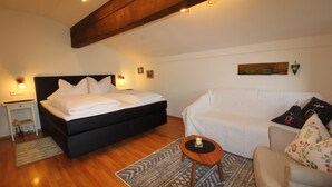 A bedroom with a bed, a sofa, a small table, and a painting on the wall. - (05) Ein-Raum-Ferienwohnung 32qm, Dusche/WC, Kochnische, Balkon (Reit im Winkl)