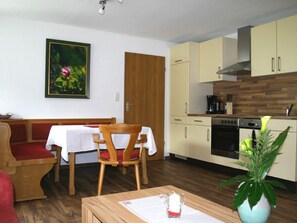 A compact living space with a dining area, kitchenette, and a single bed. - Ferienwohnung Rose, 2 Personen, 62 m², Dusche/WC, Flat-TV,1 Schlafzimmer, Balkon,Internet,Infrarot-Wärmekabine,Nichtrauch (Ramsau bei Berchtesgaden)