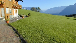 Un hotel con terraza, mobiliario exterior y vistas a las montañas.